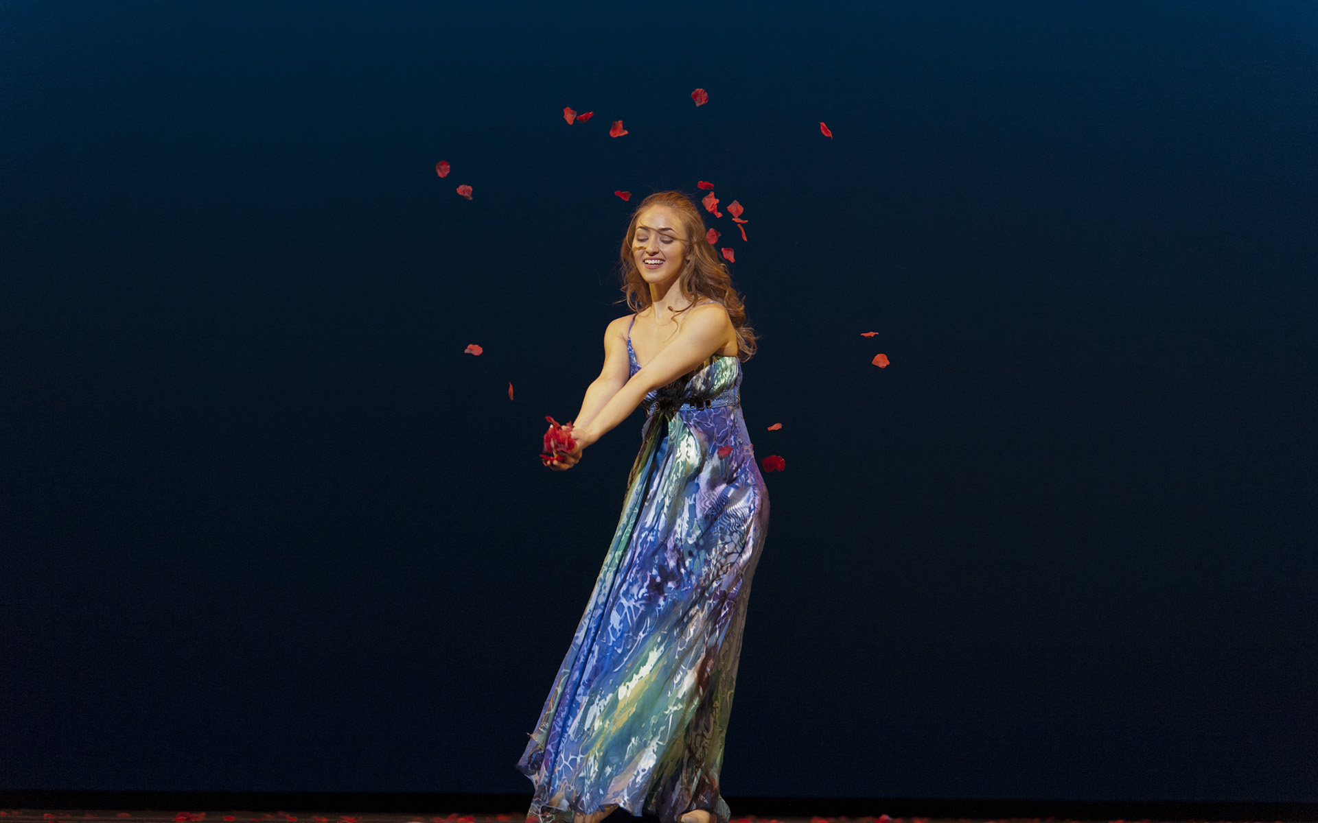 Dance Gala 2017 photo. Female dancer in blue dress throwing rose petals.